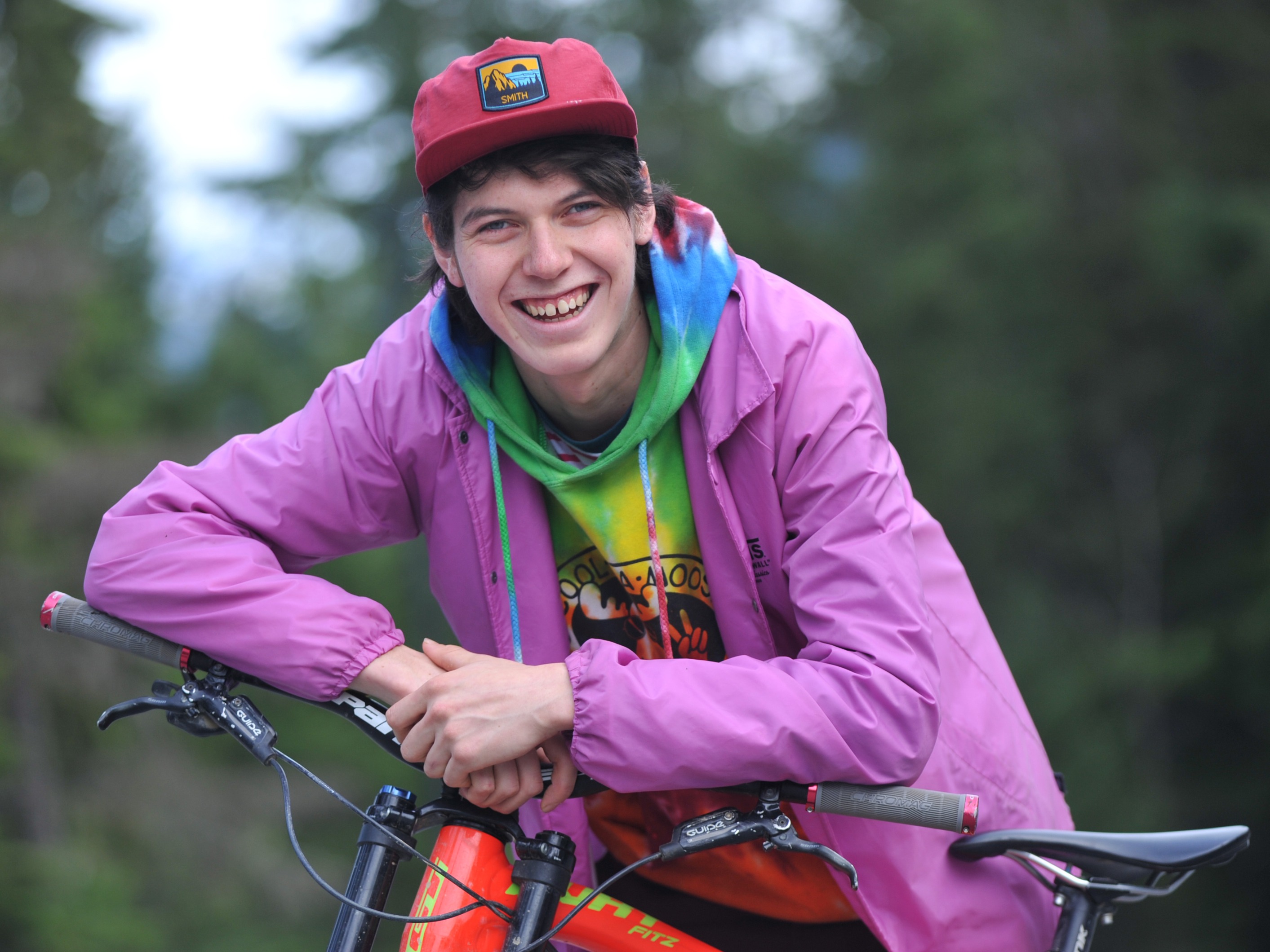 Un jeune participant de Zero Ceiling s'appuie sur son vélo et sourit à l'appareil photo

