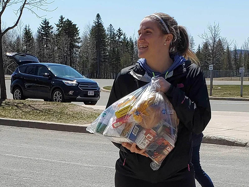 La directrice générale des Cuisines communautaires de Fredericton, Cassandra Blackmore, qui tient un sac de nourriture à livrer