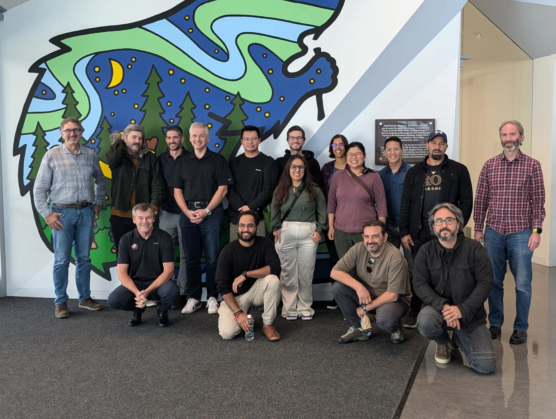 TELUS team members posing for a photograph outside of the Arctic Indigenous Perspectives exhibit at TELUS World of Science.

