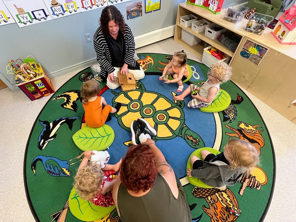 Une éducatrice enseigne des œuvres d’art autochtones à de jeunes enfants assis en cercle sur un tapis
