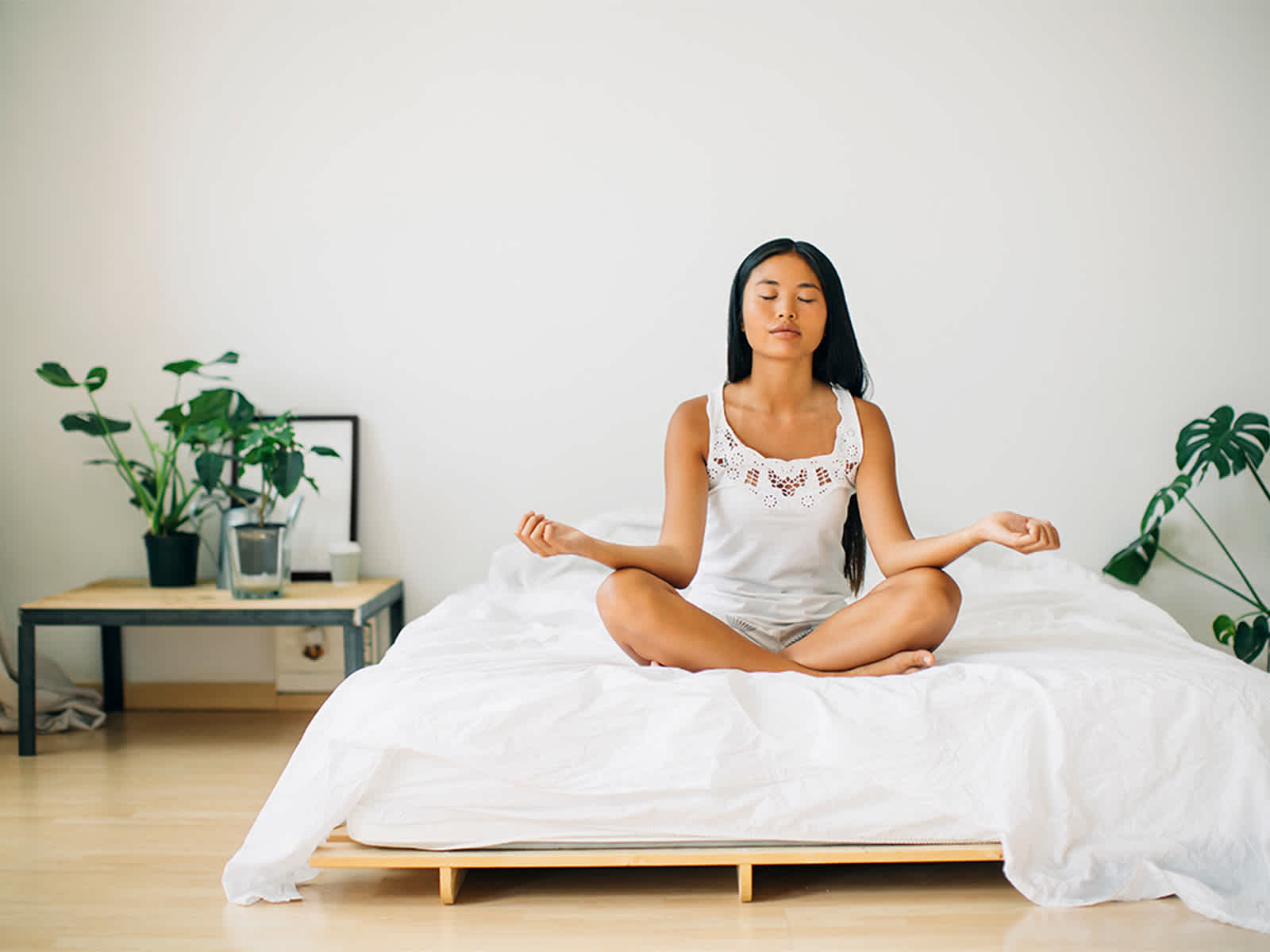 Young woman meditating on bed