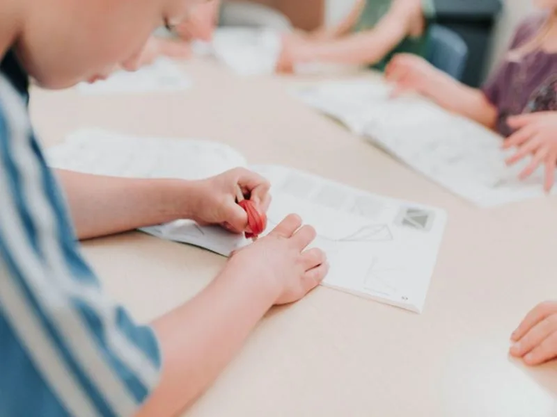 Des enfants sont assis à une table et dessinent dans un carnet de croquis. Photo via le Centre de développement de l'enfant de Prince George.