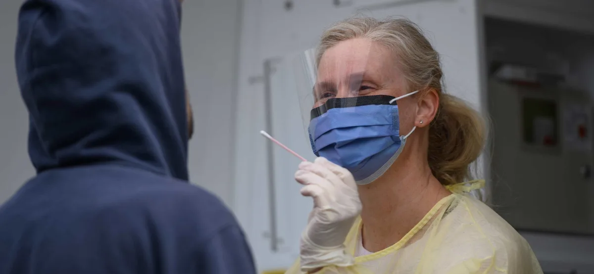 Une infirmière en équipement de protection individuelle administrant un test. 