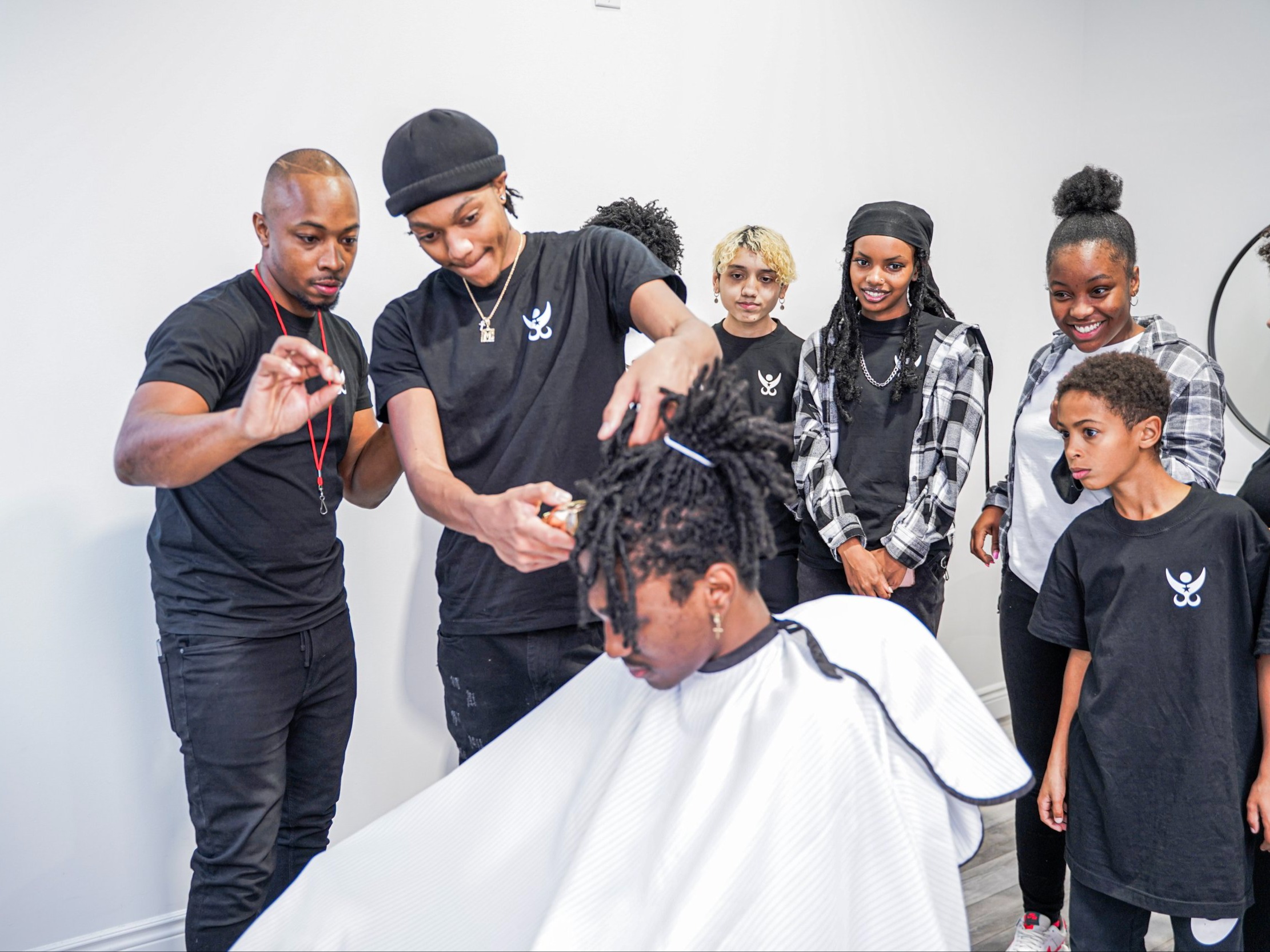 Des étudiants du programme Beyond Barbering du Bartley Skills Development Program coupent les cheveux d’un homme. 