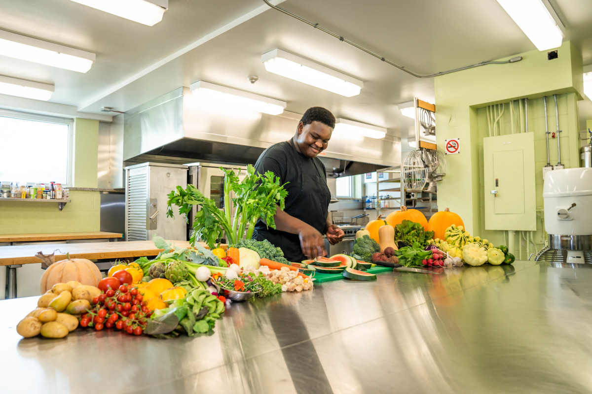 Un jeune du programme AgriLab cuisine avec des aliments cultivés par les participants du programme 