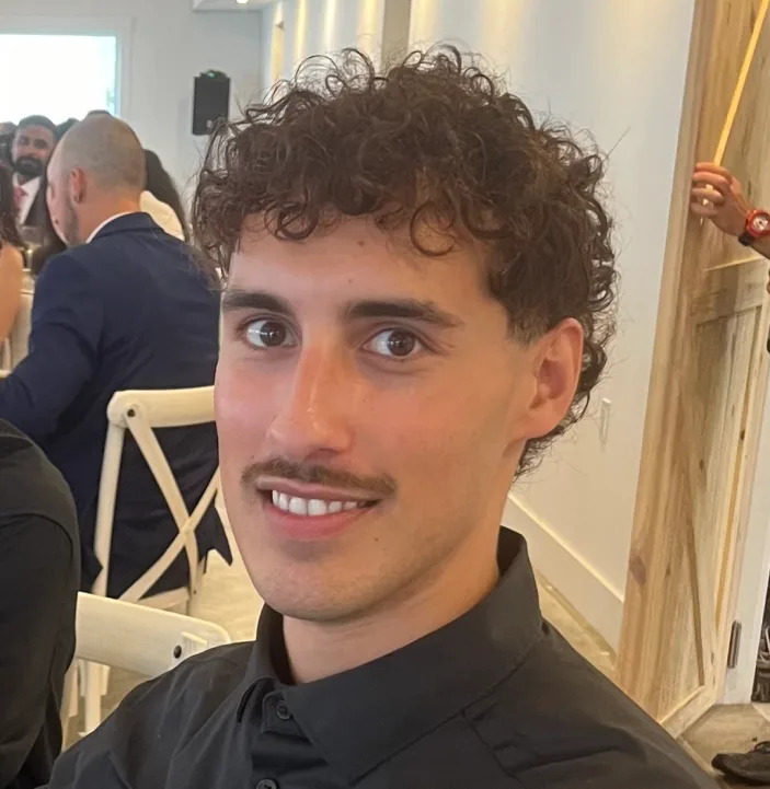 A photo of Israel at an event sitting down, looking at the camera.