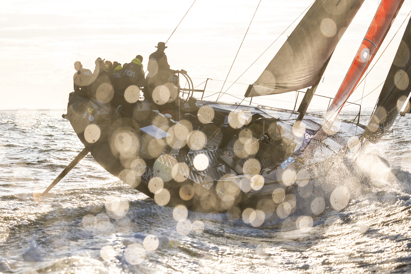Sailboat passing a lighthouse in clear weather.