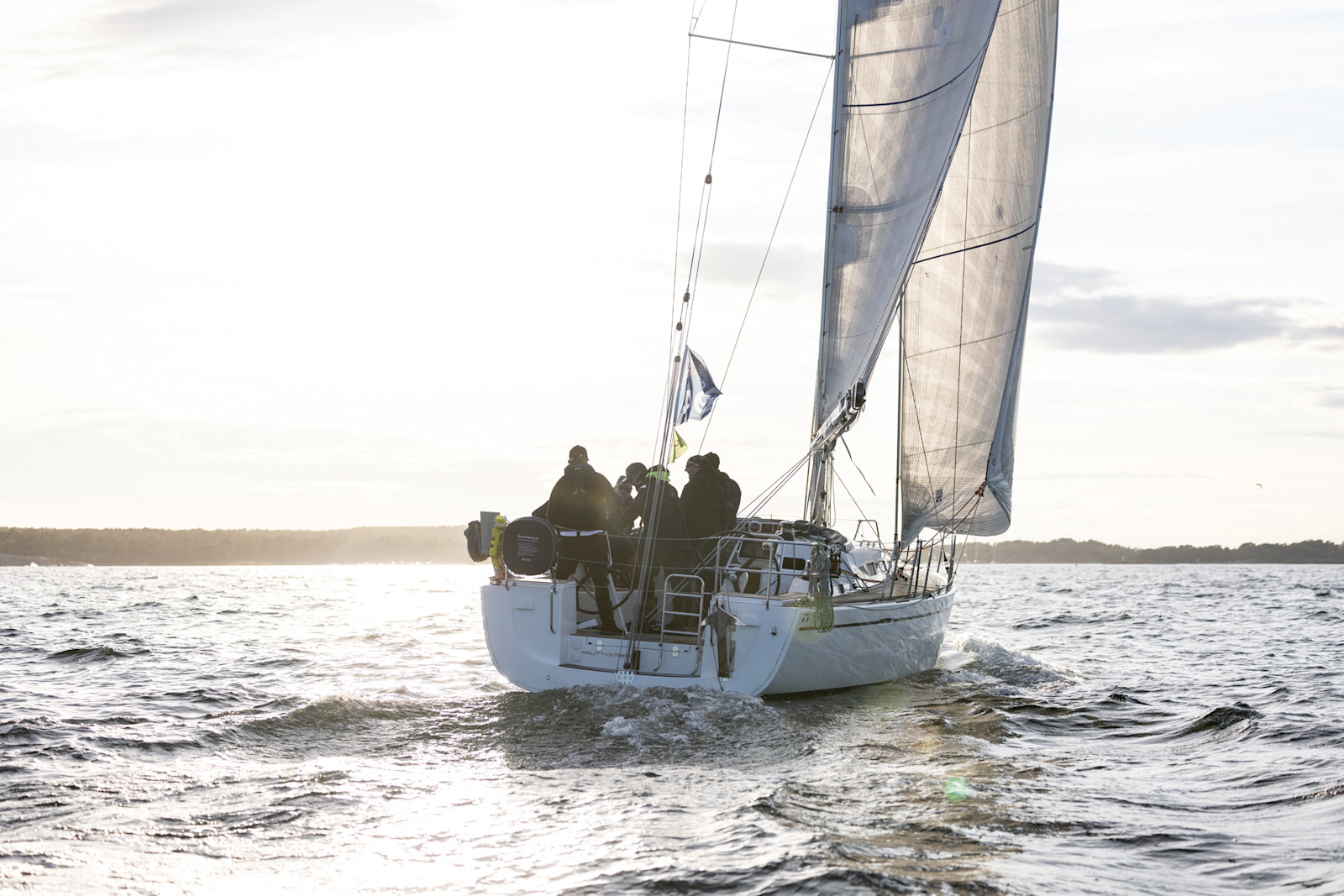 Modern racing yacht passing a lighthouse.