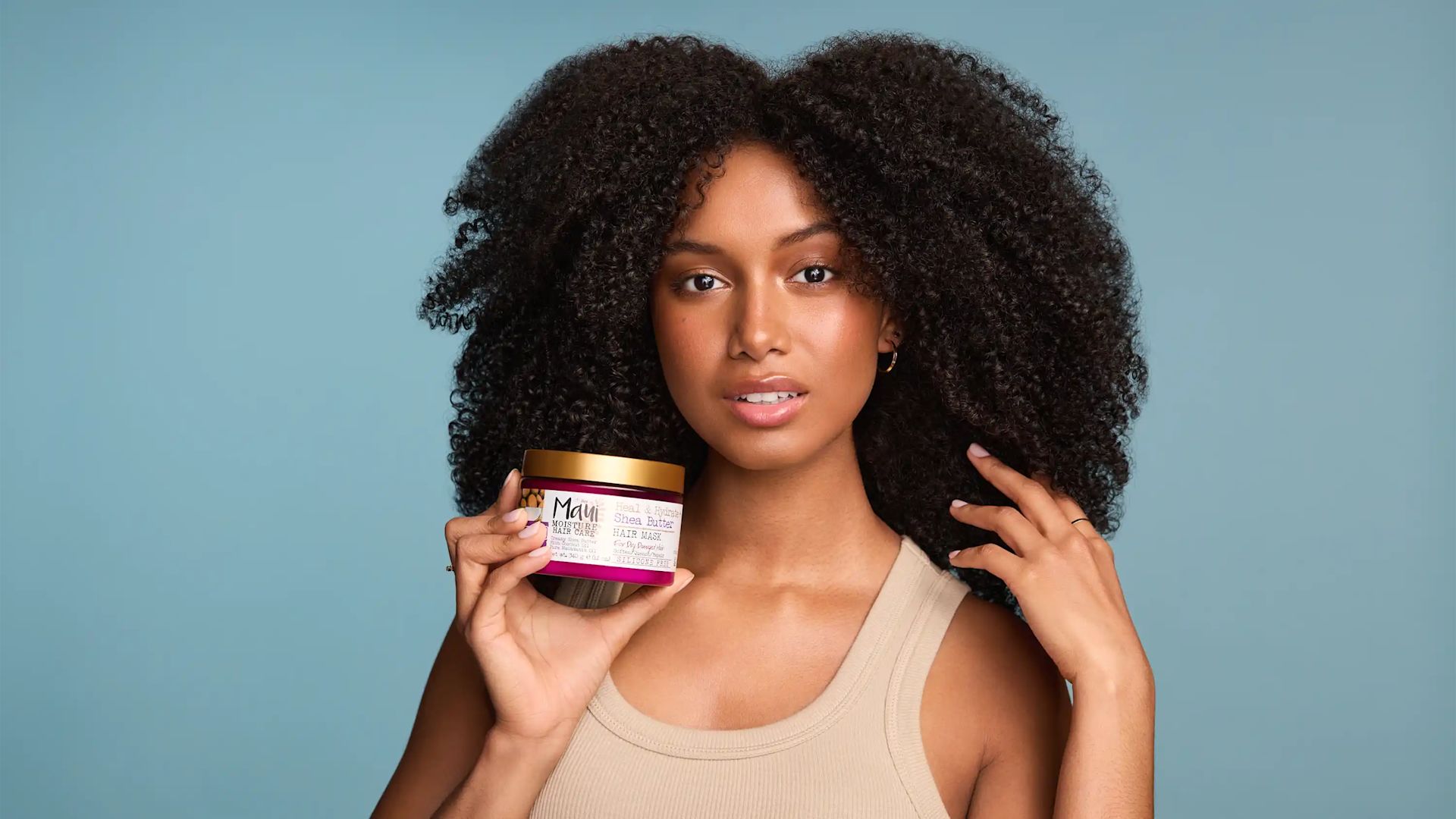 Woman with healthy curls holding Maul Moisture Heal & Hydrate + Shea Butter Hair Mask