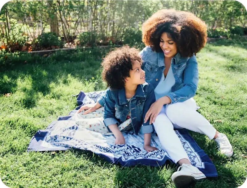 Woman and girl sitting on grass field