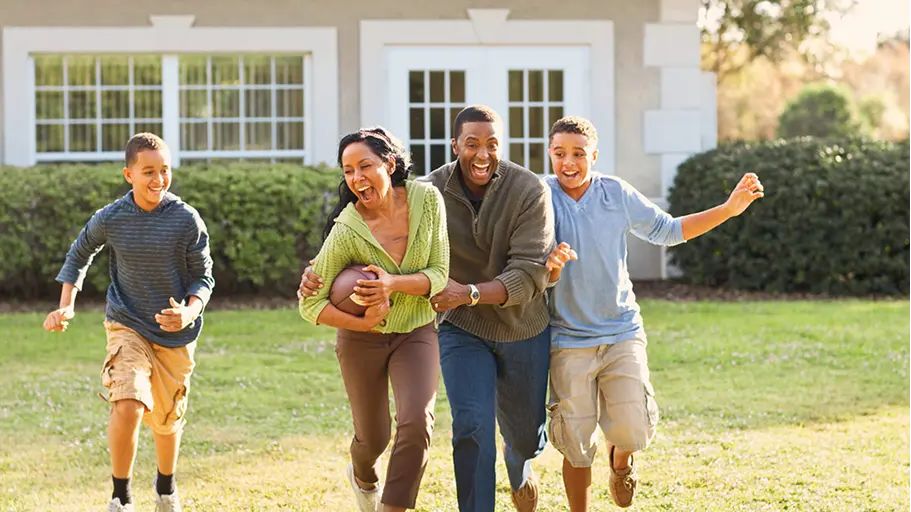 A family outside playing football together in the grass