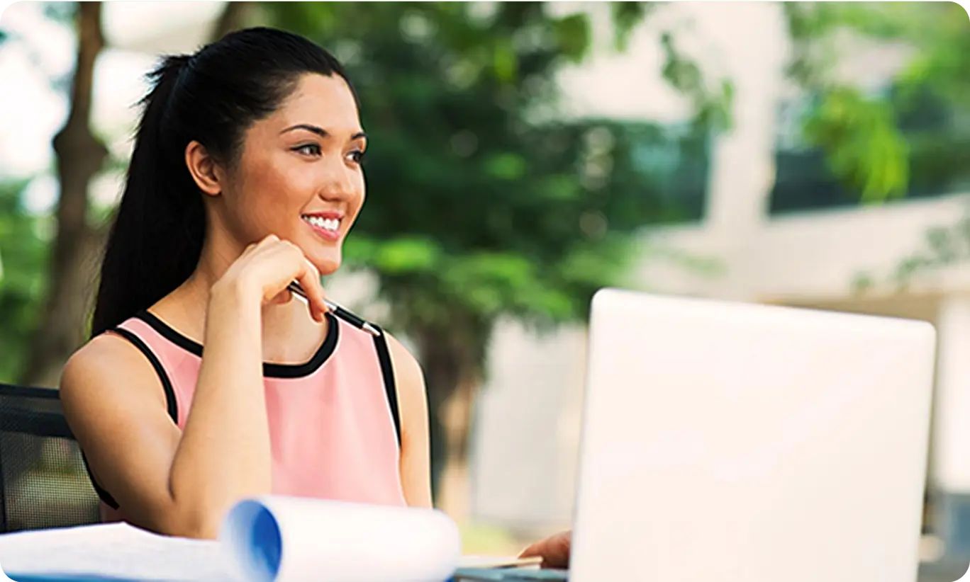 A woman sitting outside working on a laptop, representing the lifestyle of living with allergies.