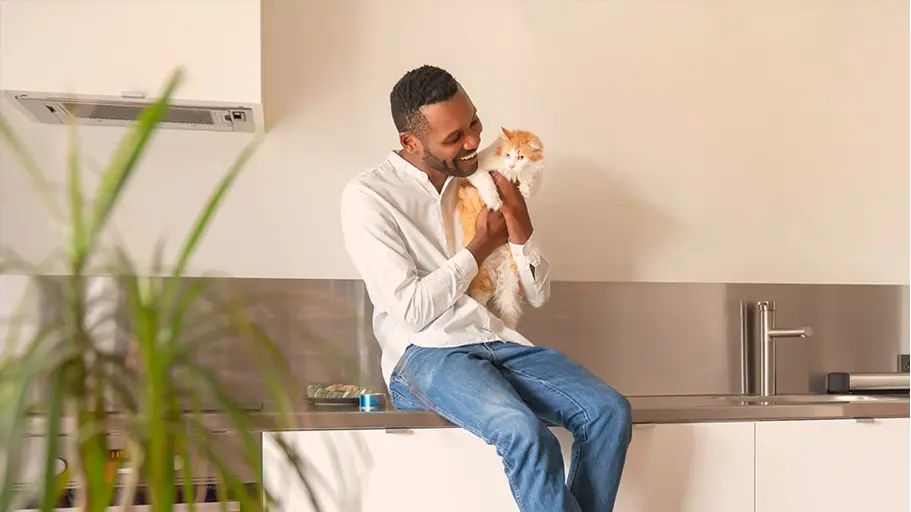 Person sitting in a kitchen holding a cat