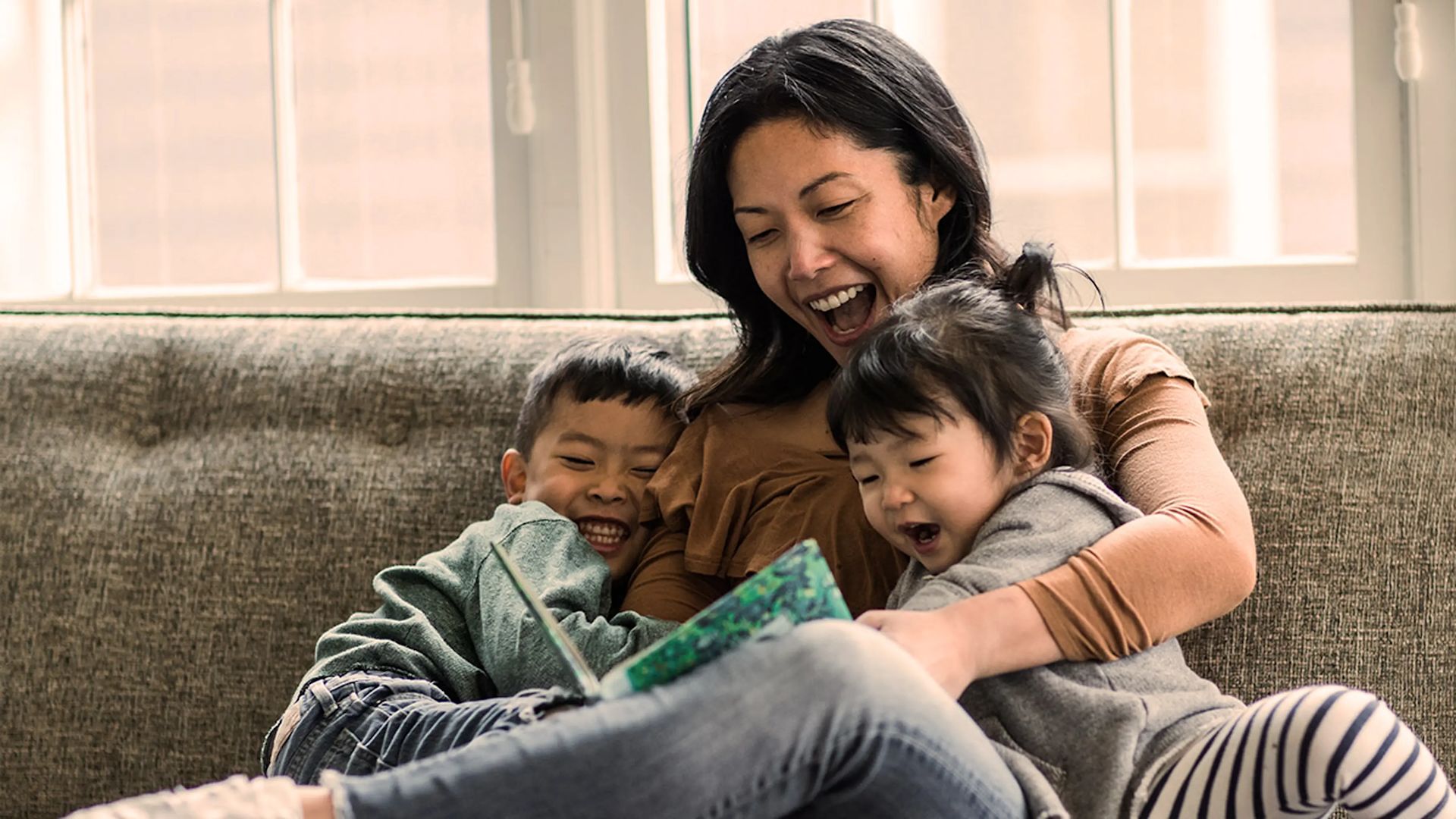 Woman sitting indoors reading to two children
