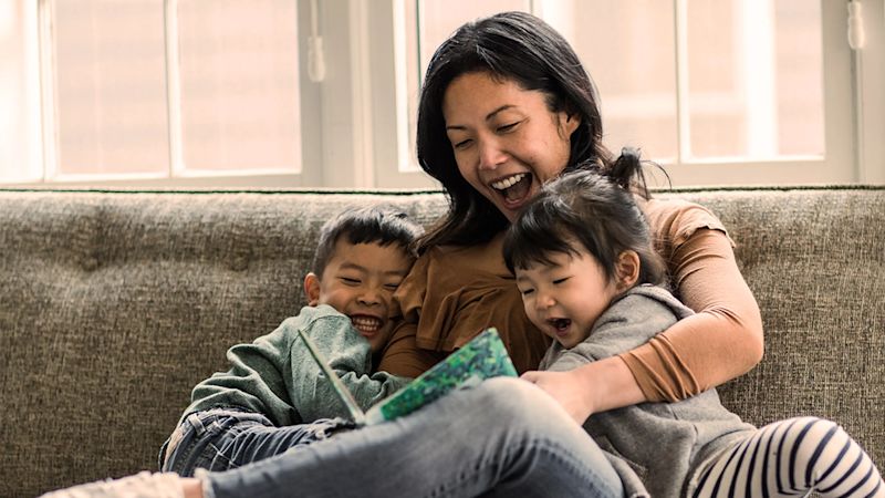 Woman sitting indoors reading to two children