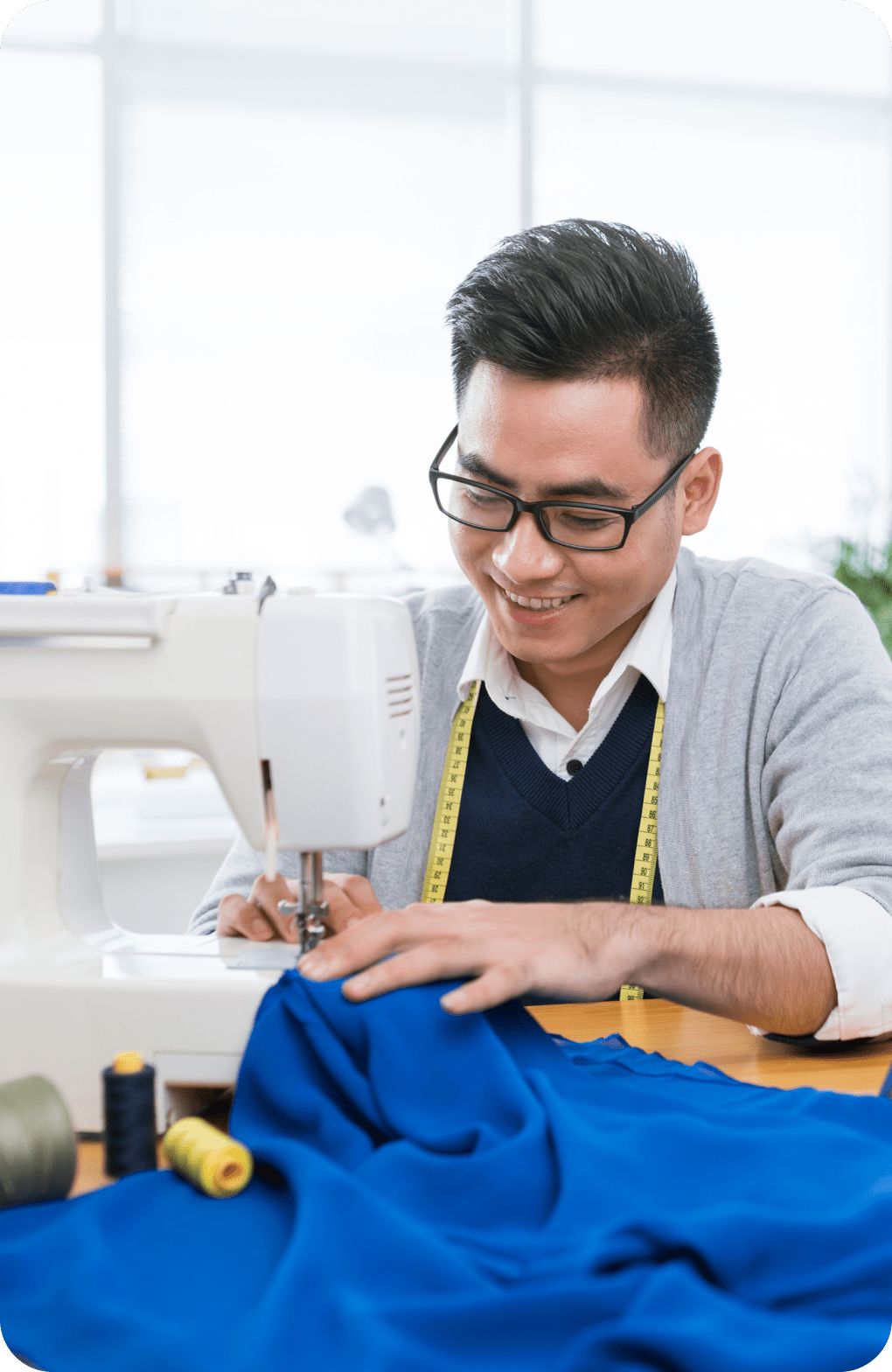 Man smiling while using a sewing machine.