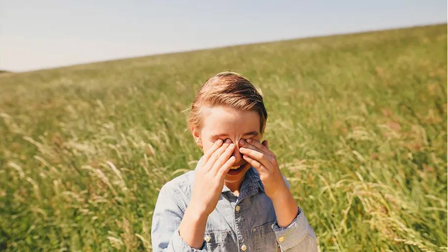 A person in a field touching their face