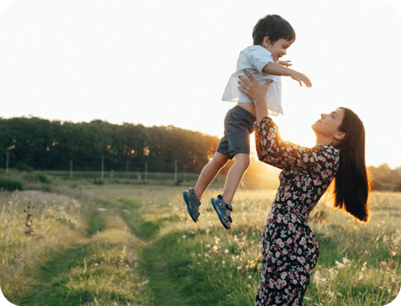 Woman in dress holding boy in field
