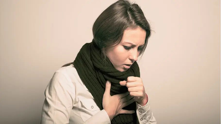 Person wearing a scarf clutching their chest experiencing congestion