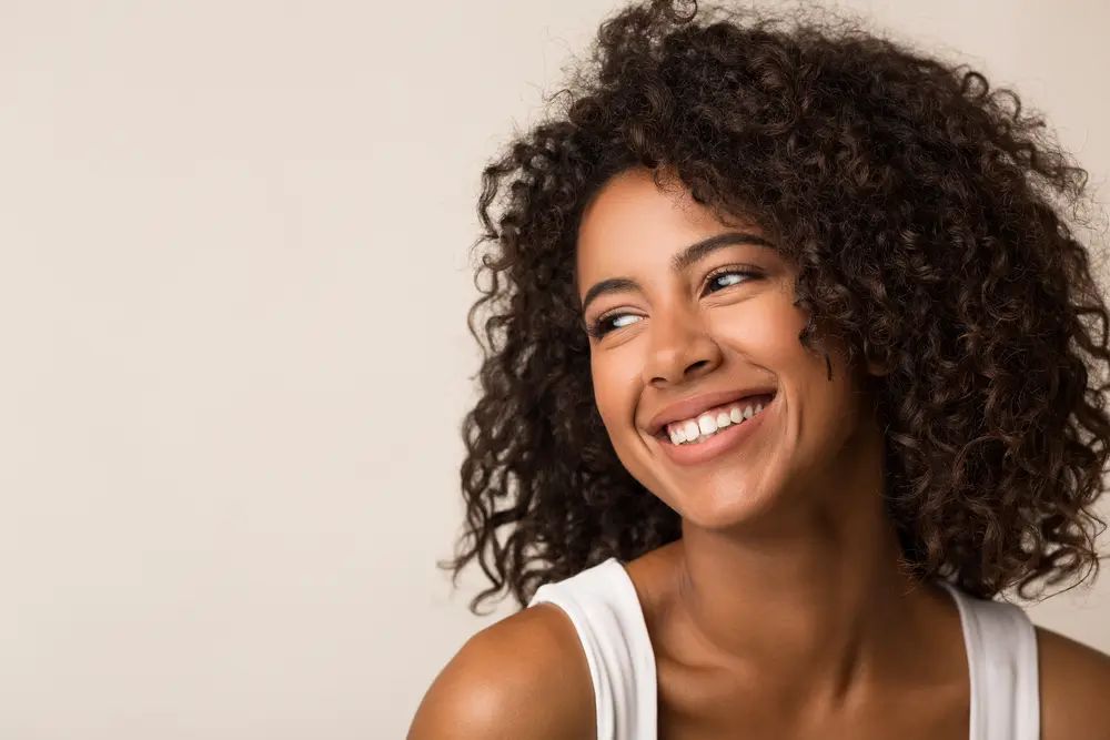 Woman with curly hair smiling after using Maui Moisture® products