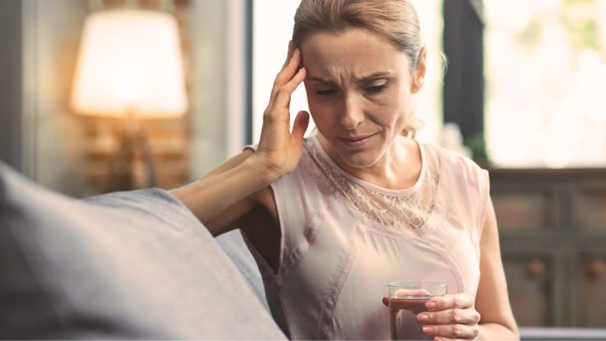 Woman with a headache holding a glass of water