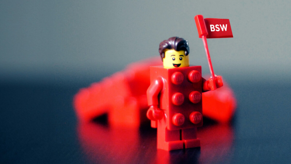 Eine rote Lego-Figur hält eine kleine BSW-Flagge hoch