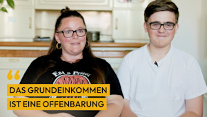 Mutter Lisa und Sohn Max sitzen vor einem Schrank. Das Bild ist durch ein Zitat ergänzt: "Das Grundeinkommen hat mich zufriedener, glücklicher und ruhiger gemacht."