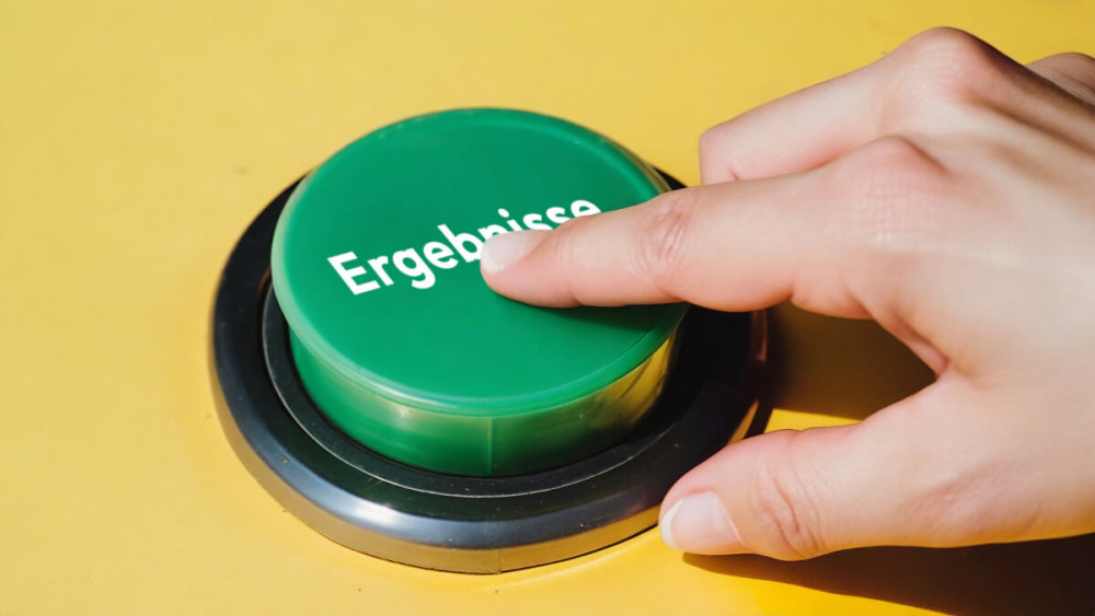 Ein FInger drückt auf einen grünen Button, der mit 