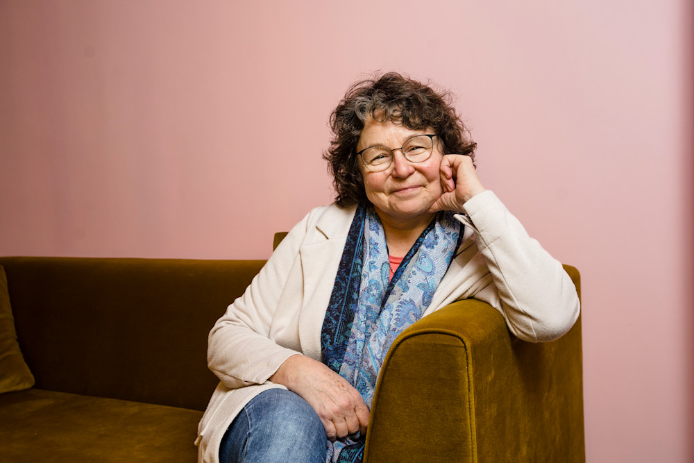Luzia sitzt entspannt auf einem Sofa und schaut in die Kamera