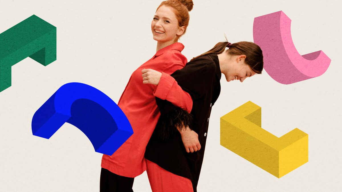 Zwei Frauen albern herum, die eine nimmt die andere Huckepack. Um sie herum fliegen bunte, geometrische Symbole in der Luft, die an Spielklötzchen erinnern.