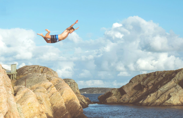 Ein Mensch springt von einem Felsen ins Wasser