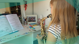 Gewinner*innen-Kind Dafina steht vor ihrem Spiegel und spielt Saxophon. 