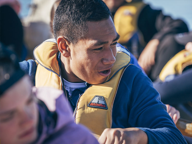 A young male excited to be rowing on a cutter at Outward Bound