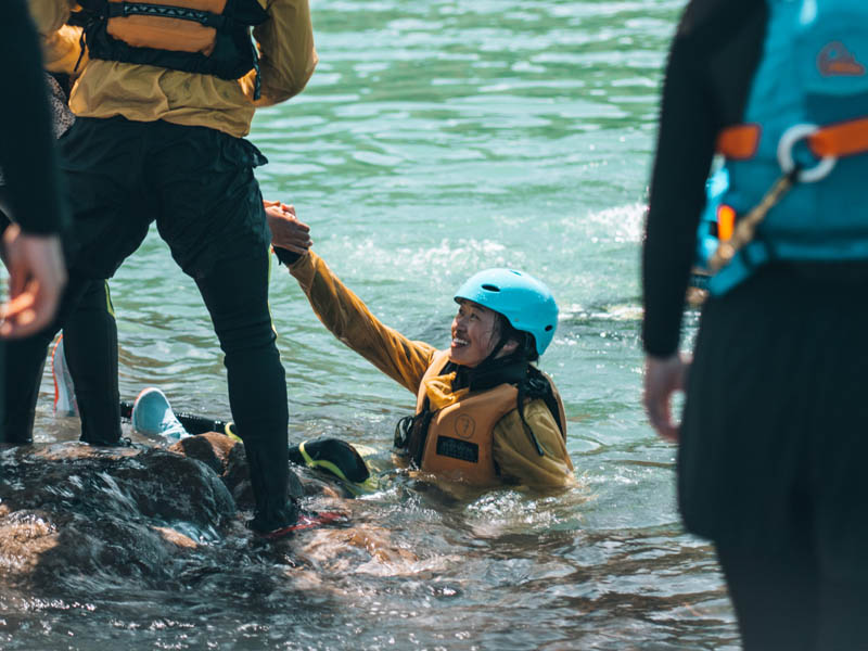 An instructor offering their hand to a student while coasteering