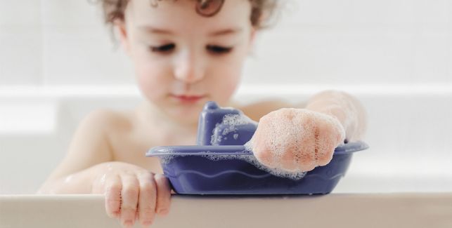 petit garçon assis dans la baignoire jouant avec ses jouets de bain