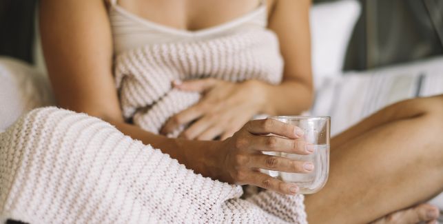 femme assiste sur le canapé avec un verre d'eau