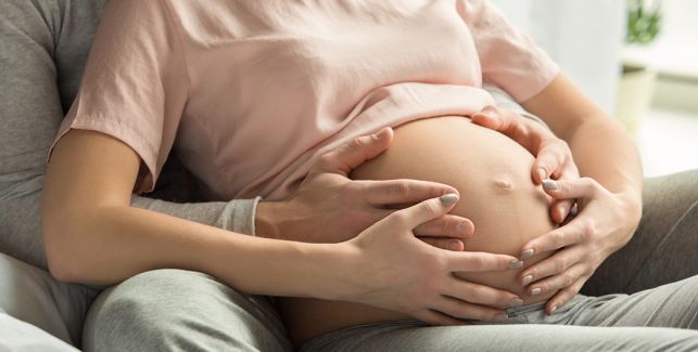 Madre e partner tengono le mani sulla pancia della mamma