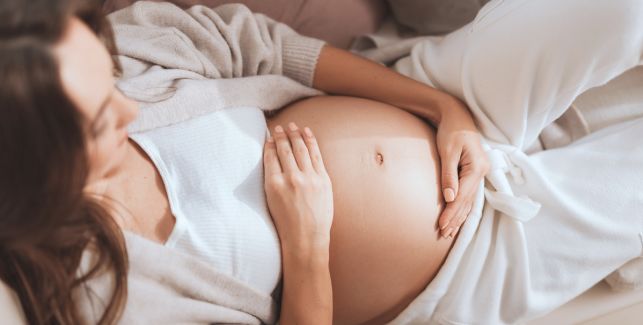 Schwangere Frau berührt ihren Bauch.