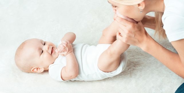 Mutter kitzelt die Füße ihres Babys als Teil der Babymassage