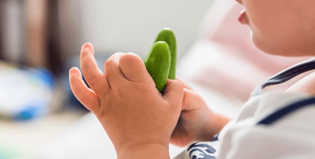 Bambino con in mano della verdura