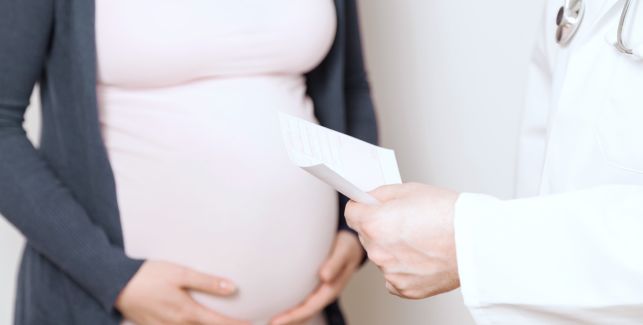 Schwangere Frau hält sich ihren Babybauch und wird von einem Arzt beraten.