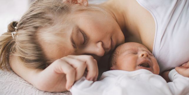 Mutter liegt mit Baby Blues neben ihrem Neugeborenen
