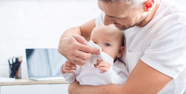 Vater mit seinem Baby, das Schnupfen hat.