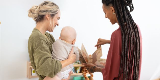 Zwei Mamas schauen sich mit ihrem Baby ein Bilderbuch an