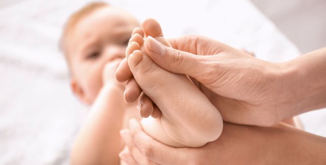 Baby bekommt von Osteopathen den Fuß massiert.
