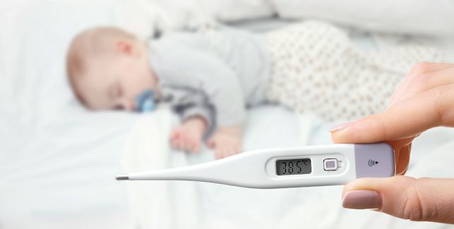 Mamá tomándole temperatura a su bebé enfermo dormido