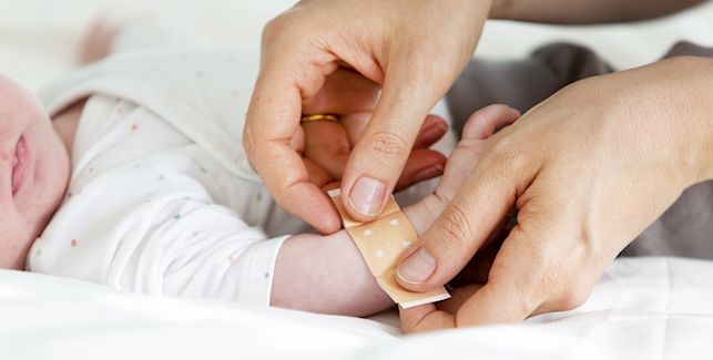 Maman qui colle un pansement sur le bras de son bébé