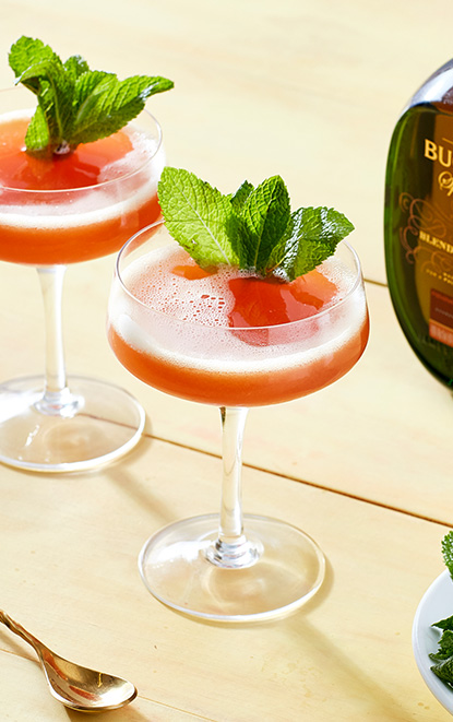 Two complex, colorful, & eminently sippable Swinging Sword cocktail next to a bottle of Buchanan’s 18-Year-Old Special Reserve Blended Scotch Whisky