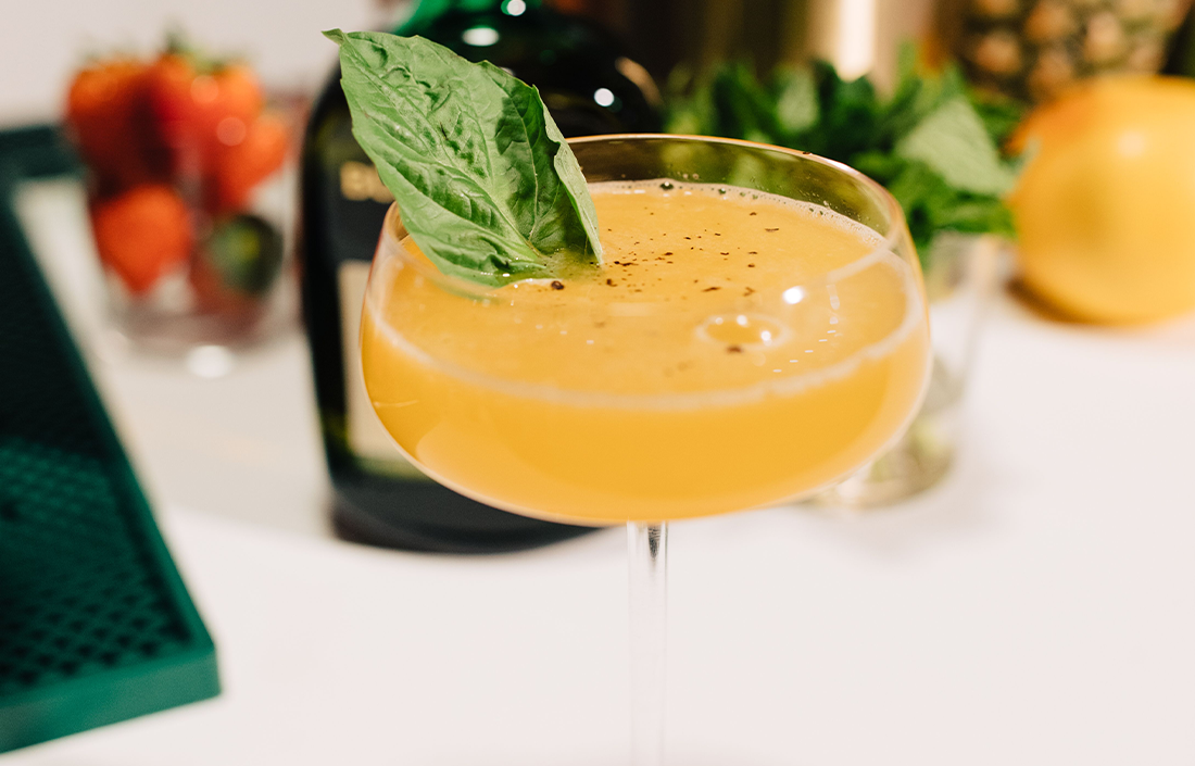 The Buchanan's peppered pineapple drink in a martini glass and garnished with a basil leaf