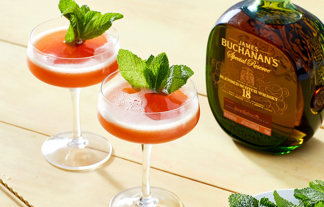 Two complex, colorful, & eminently sippable Swinging Sword cocktail next to a bottle of Buchanan’s 18-Year-Old Special Reserve Blended Scotch Whisky